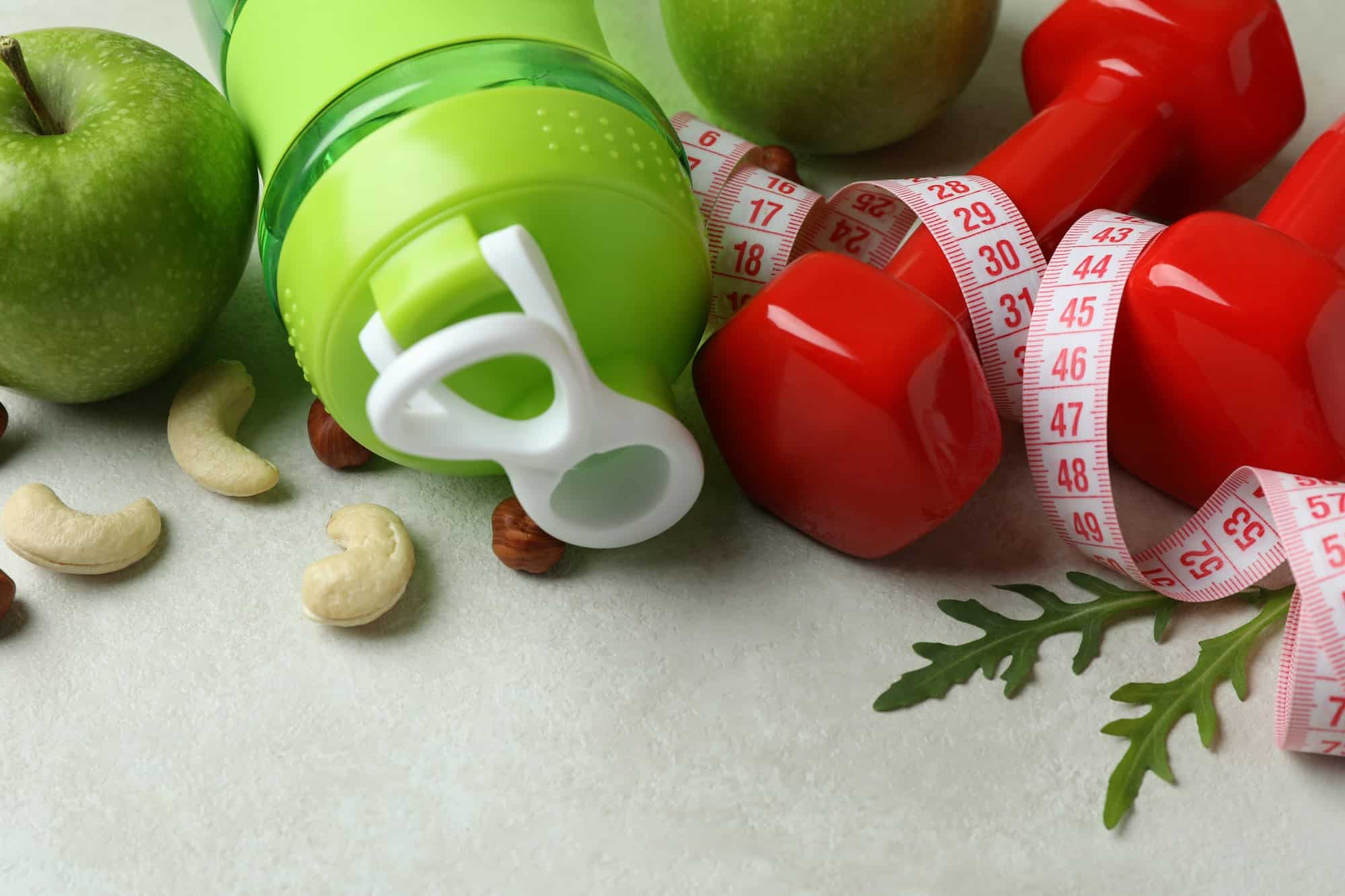Weight loss accessories on white textured background, close up