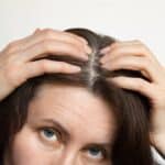 A middle-aged woman shows gray hair roots.