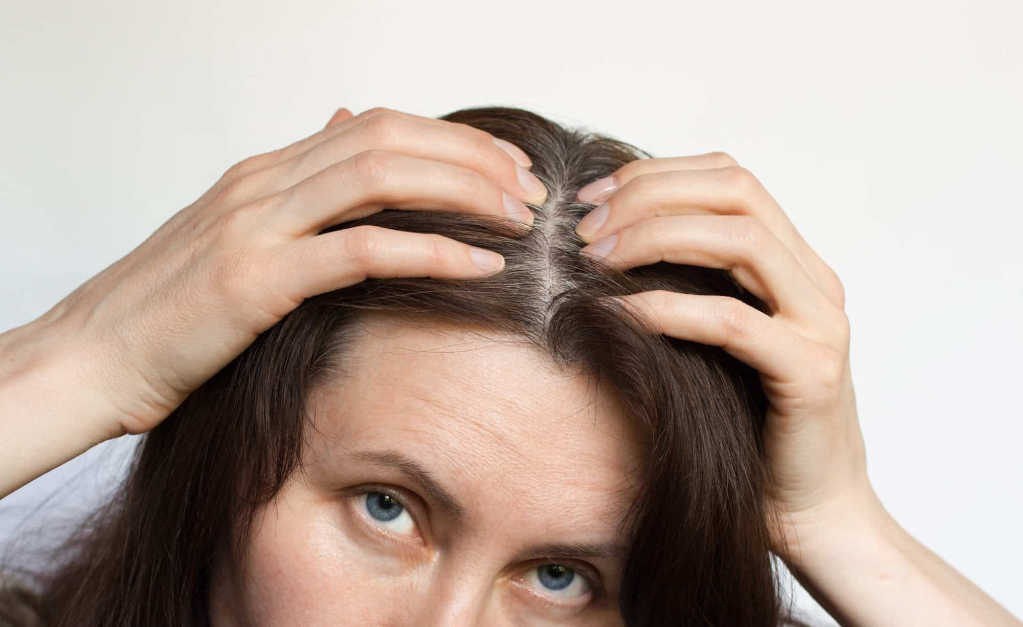 A middle-aged woman shows gray hair roots.
