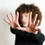 Defocused woman stretching arms and showing stop gesture with full open palms