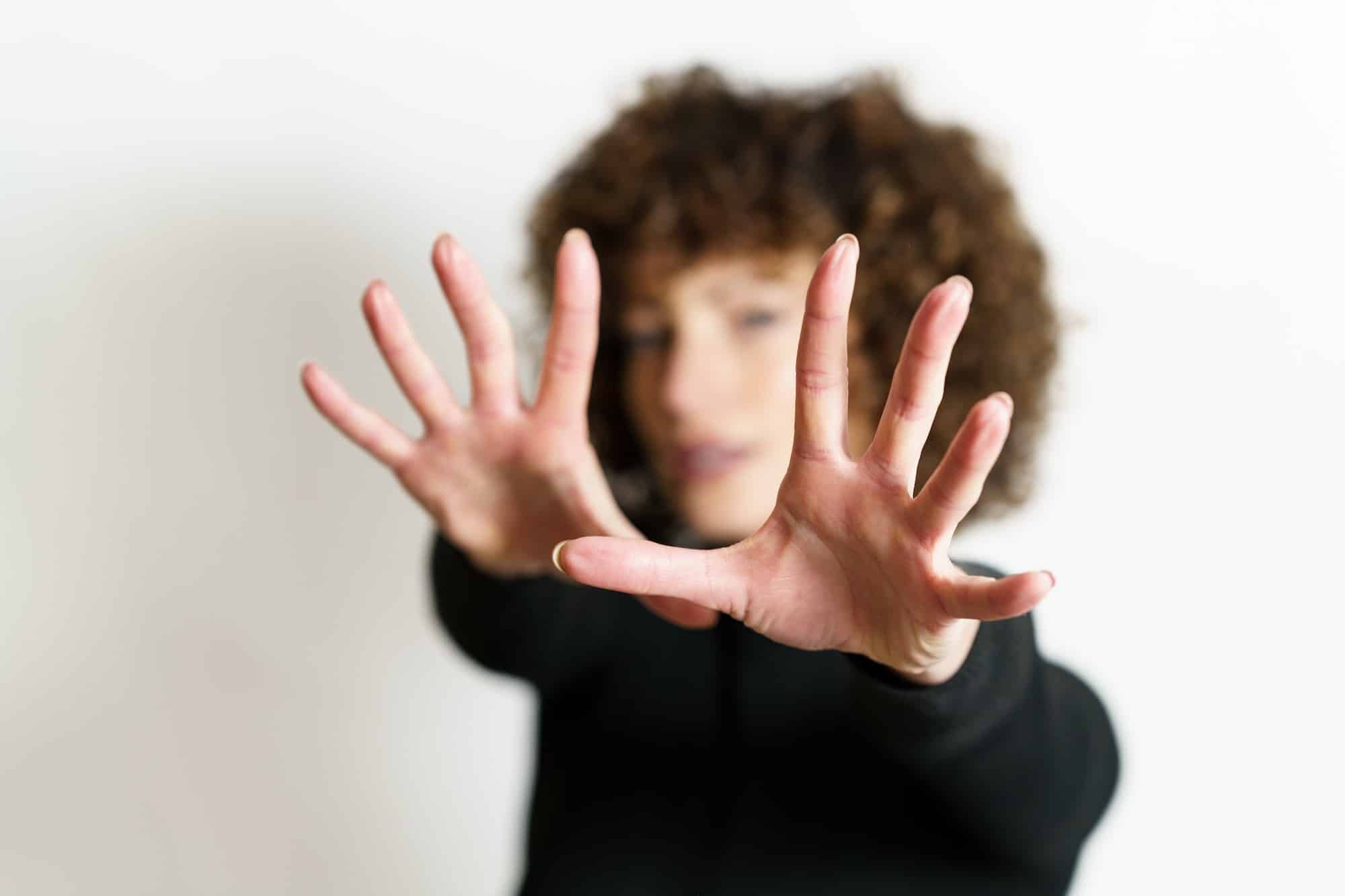 Defocused woman stretching arms and showing stop gesture with full open palms