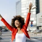 Portrait of happy young woman with smartphone wearing fashionable red suit jacket