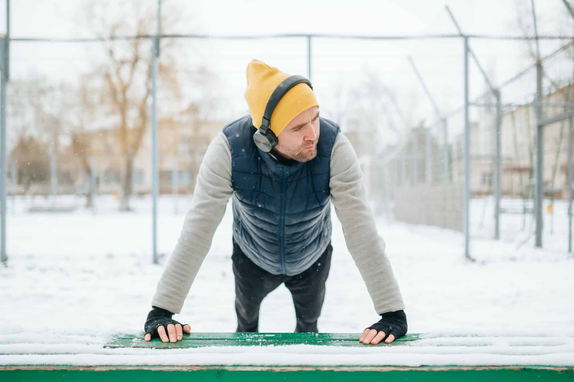 Young Man Living an Active Life with Headphones in Wintertime Gymnastics and Athletics