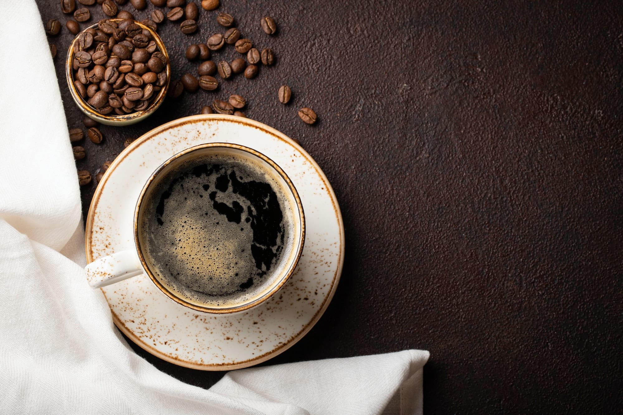 Close-up of a Cup of black coffee and coffee beans on a dark background. Top view with copy space