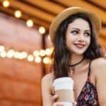 Shy brunette female with dark eyes and red lips wearing straw hat and dress