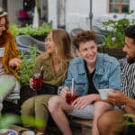 groupe de jeunes gens heureux assis dans un café en plein air lors d'un voyage en ville, parlant.