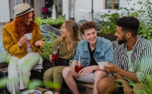 groupe de jeunes gens heureux assis dans un café en plein air lors d'un voyage en ville, parlant.