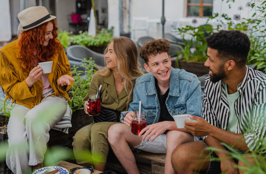 groupe de jeunes gens heureux assis dans un café en plein air lors d'un voyage en ville, parlant.