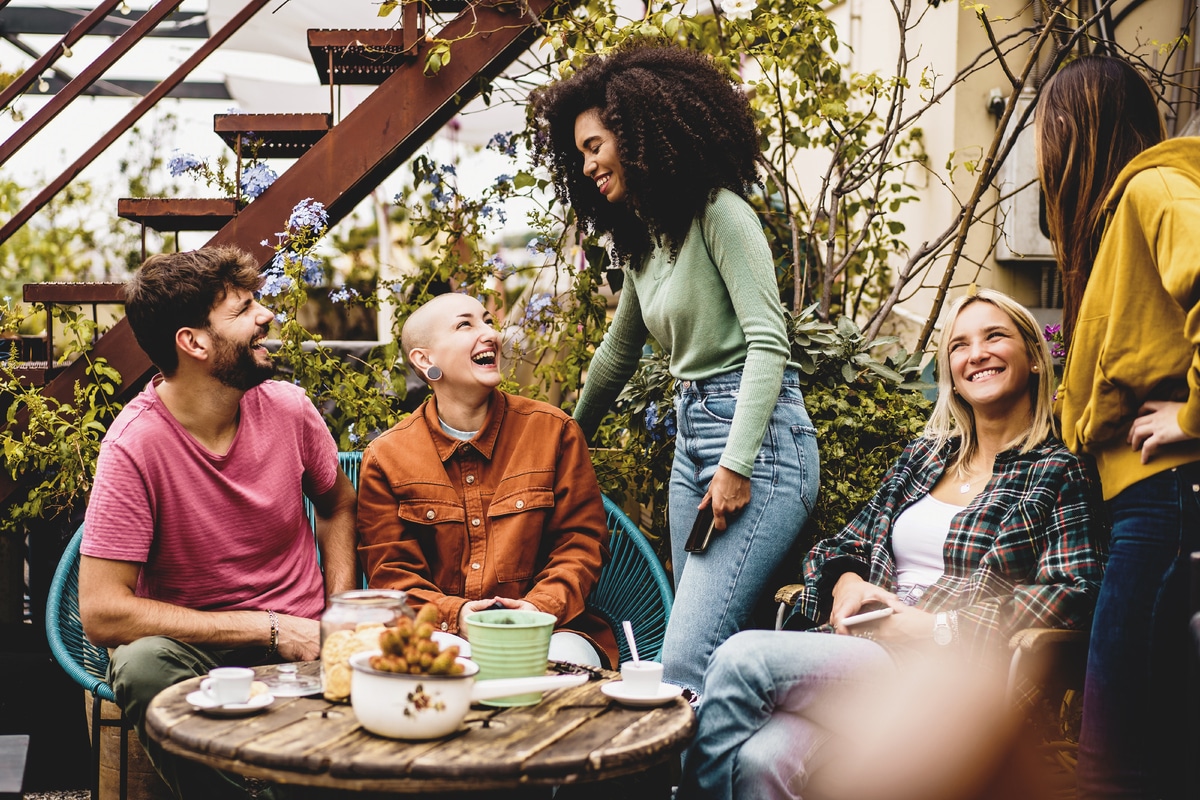 des personnes multiethniques de la génération z se rassemblent sur la terrasse de l'auberge pour boire du café et parler ensemble