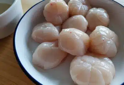 Noix de Saint-Jacques crues disposées sur un plateau de cuisine