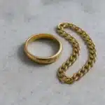 Bijoux en or ternis avant nettoyage, bague et chaîne ternes posées sur une surface neutre
