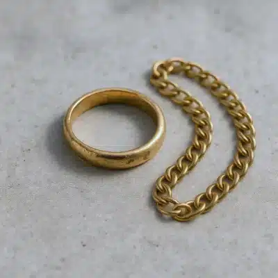 Bijoux en or ternis avant nettoyage, bague et chaîne ternes posées sur une surface neutre