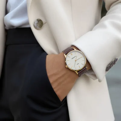 Personne élégante portant une montre classique au poignet gauche, tenue chic et lumière naturelle