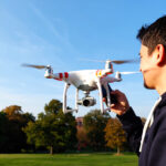 Jeune homme pilotant un mini-drone débutant dans un parc ensoleillé